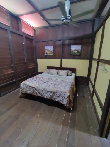 Kampong Ulu KalongPort Mancing Fishing Village的铺有木地板的客房内设有一间卧室和一张床。