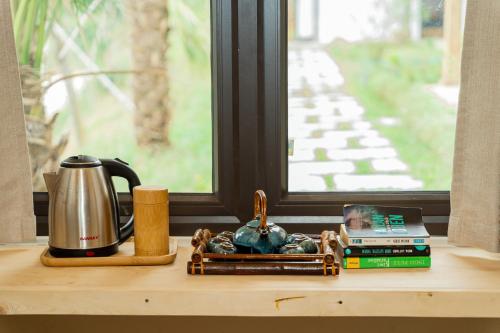 河内6Nature Bavi Retreat的一张桌子、咖啡壶、书籍和窗户