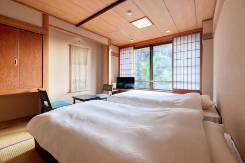 南小国町Yukyo no Hibiki Yusai的一间卧室设有两张床和窗户。