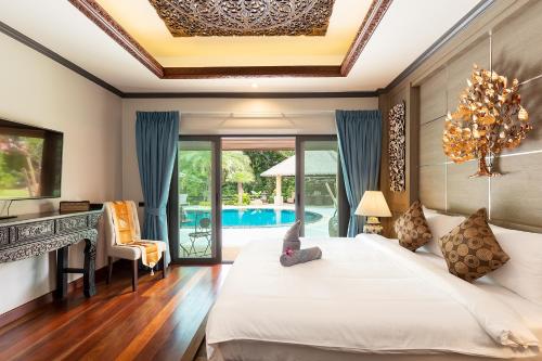 拉威海滩Villa Carlos, Luxury 7 BDR Private Pool Villa, Baan Bua Nai Harn, Phuket的一间卧室配有一张床和一张书桌,还有一个游泳池