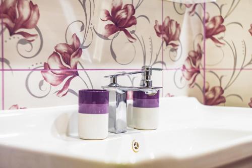 大特尔诺沃KRISSTY Apartment的浴室设有水槽,墙上挂着紫色的鲜花