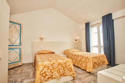 圣特雷莎加卢拉Hotel Muita di Mari的一间卧室设有两张床和窗户。