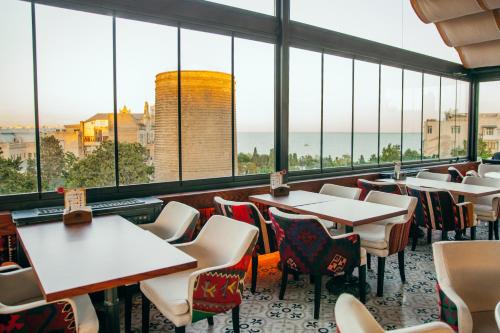 巴库苏丹精品酒店的餐厅设有桌椅和大窗户。