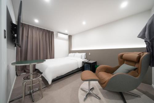 仁川市Jawoori Hotel Incheon Songdo的酒店客房带一张床、一张桌子和椅子