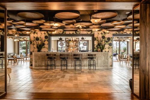 圣蓬萨Kimpton Aysla Mallorca, an IHG Hotel的一间设有酒吧的房间,配有凳子和桌子