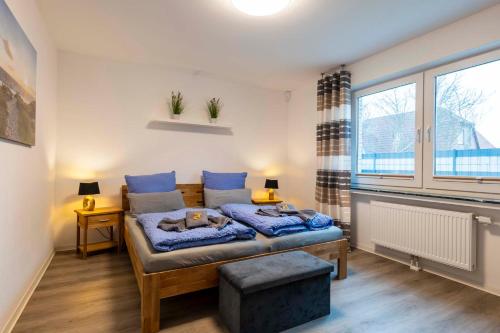 诺登Küsters Ferienhaus Tinchen的一间卧室配有一张带蓝色床单的床和一扇窗户。