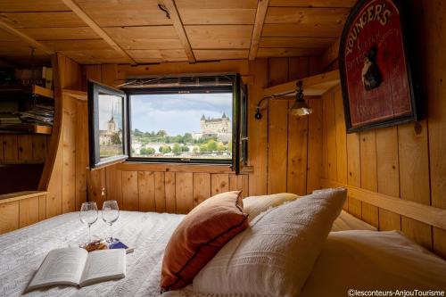 索米尔BATEAU LE VENT DE TRAVERS的一间卧室配有一张带窗户的床和两杯酒杯