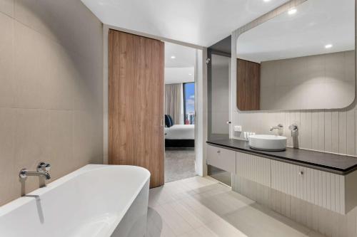 墨尔本Adina Apartment Hotel Melbourne Southbank的带浴缸、水槽和镜子的浴室