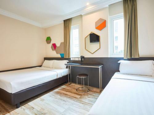 新加坡ibis budget Singapore Emerald的酒店客房配有两张床和一张书桌