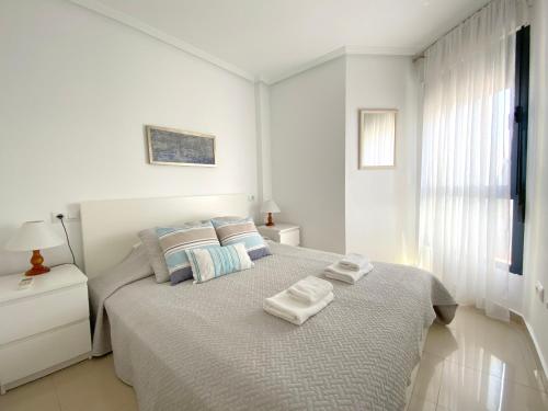奥里韦拉海滩REGIA BAHIA - Cabo Roig - SEA VIEW的白色卧室,配有带毛巾的床