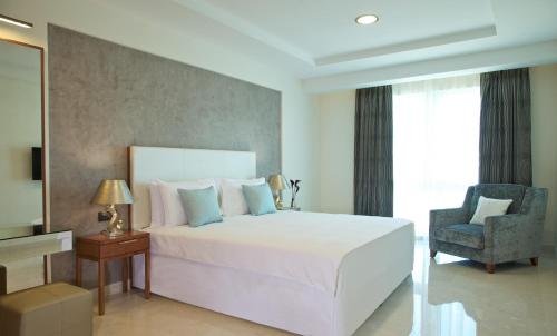 马斯喀特马斯喀特千年行政公寓酒店的卧室配有一张白色大床和一把椅子