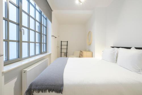 布鲁塞尔Appartement design 3 chambres proximité Grand-Place Bruxelles的白色卧室设有大床和窗户