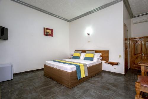 KoldaHôtel le Relais de Kolda的一间卧室配有一张大床,提供黄色和蓝色的枕头