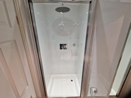 纽比桥兰丁小屋宾馆的浴室里设有玻璃门淋浴
