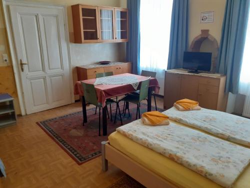 维也纳快乐旅馆的一间设有两张床和一张桌子及椅子的房间