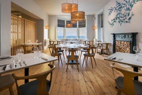 利扎尔德Housel Bay Hotel的餐厅设有桌椅和大窗户。