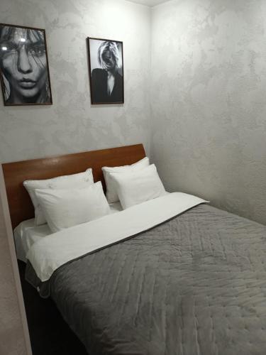 彼得罗巴甫洛夫斯克Уютная и просторная квартира в 50 метрах от городского парка的卧室内的一张床铺,墙上有两张照片