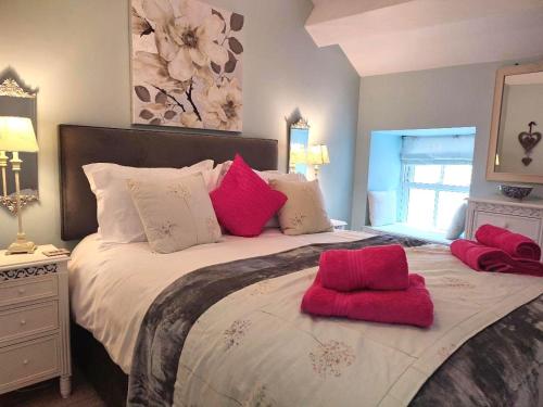 纽比桥Woodside Cottage with free Spa access的一间卧室配有一张带红色枕头的大床