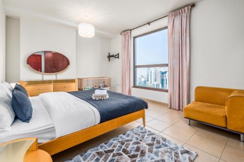 迪拜Lovely 2-bed condo in JBR - 5 mins from beach - Palm View!的卧室配有床、椅子和窗户。