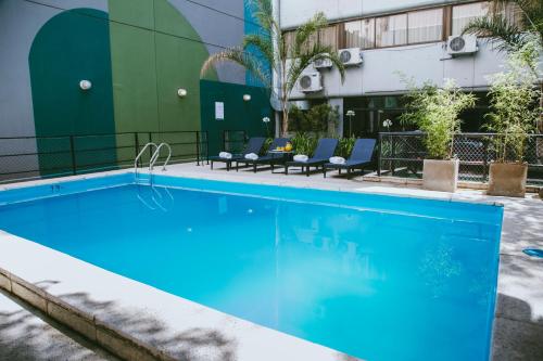 布宜诺斯艾利斯Deco Collection的一座带椅子的酒店游泳池,一座建筑