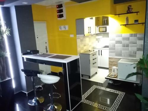 贝尔格莱德Spa Apartment的厨房设有黄色的墙壁和带凳子的柜台。