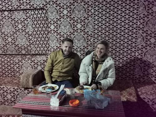瓦迪拉姆Shahrazad desert, Wadi Rum的坐在餐桌旁吃饭的男人和女人