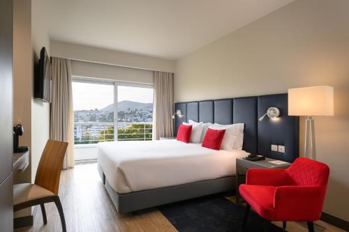 塞图巴尔塞图巴尔美利亚酒店的酒店客房设有一张大床和一张红色椅子。