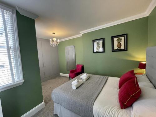 布莱顿霍夫Regency Apartment - Marine Square By Crown Gardens Holiday Homes的一间卧室设有绿色的墙壁和一张带红色枕头的床