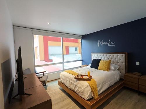 墨西哥城Luxury Condo Santa Fe Cosmocrat By Bamboo Skylife的一间卧室设有一张床、一台电视和一个窗口。