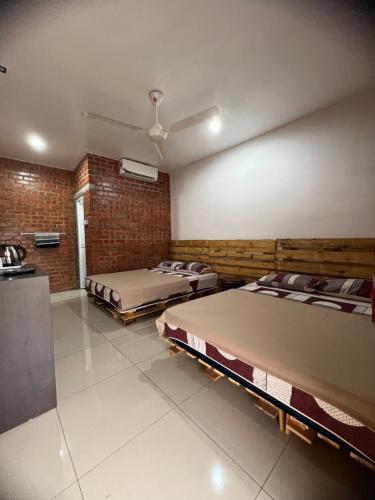 马六甲Ujud Sepakat Homestay的一间设有两张床和砖墙的房间