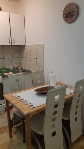 斯雷姆斯卡米特罗维察Sirmijum Hause的厨房配有木桌、椅子和时钟