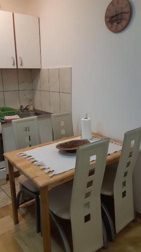 斯雷姆斯卡米特罗维察Sirmijum Hause的厨房配有木桌、椅子和时钟