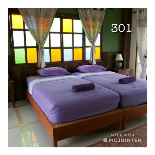 清刊เชียงคานบุรี的带窗户的客房内的两张床和紫色床单