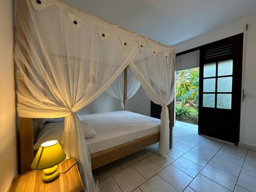 拉特里尼泰Villa Grenadille的一间卧室配有天蓬床和一盏灯。