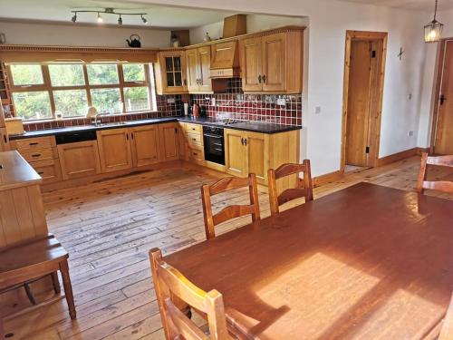 莱特肯尼Comfortably Crolly Holiday Home的厨房配有木制橱柜和一张带椅子的木桌