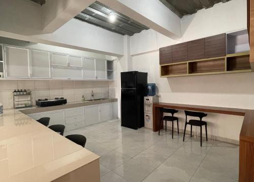 雅加达9 Residence Guesthouse Syariah Cilandak的厨房配有黑色冰箱和一些椅子