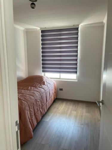 伊基克Departamento con vista al mar的一间卧室配有一张床和一个带百叶窗的窗户
