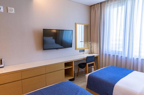 光阳光阳吉祥酒店的酒店客房配有一张床和一张书桌及一台电视