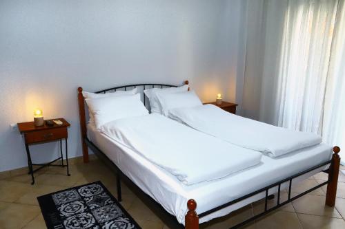 兹拉马Ourania Apartment的一间卧室配有两张带白色床单和两张蜡烛的床。