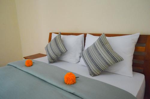 珀尼达岛Maja House Penida的一张带白色枕头的床和橙色的鲜花