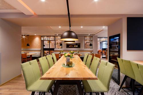 曼德沙伊德海斯穆勒酒店的一间带木桌和绿色椅子的用餐室