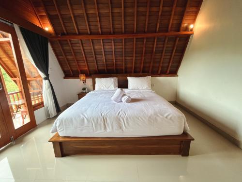 batumadegdbelish village & resto的卧室配有白色床和木制天花板