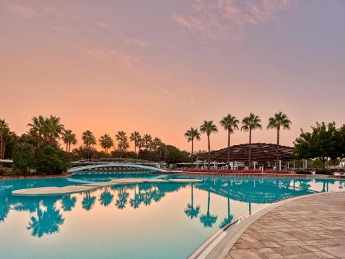 拉瑞Lara Barut Collection-Ultra All Inclusive的棕榈树泳池和日落背景