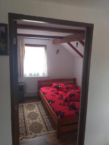科利比塔Cabana Bradul的一间卧室配有一张带红色床单的床和一扇窗户。
