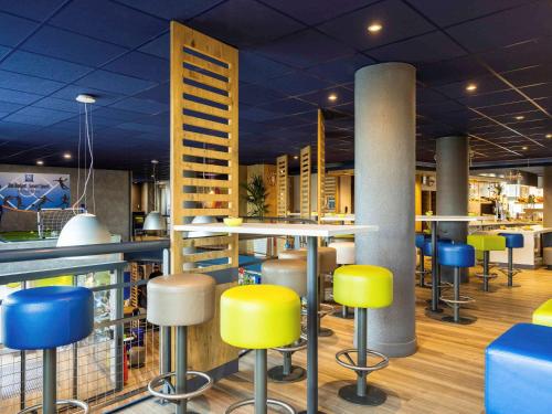 巴黎奥尔良门宜必思快捷酒店的餐厅里设有黄色和蓝色凳子的酒吧