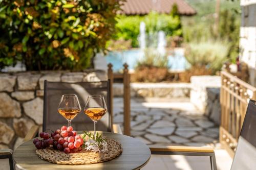 塞沃塔Sivota Diamond Spa Resort的一张桌子,上面放着两杯葡萄酒和葡萄
