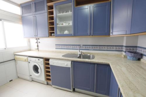 塞维利亚Sevilla Clásica: amigos y familia. Parking gratis!的厨房配有蓝色橱柜和洗衣机。