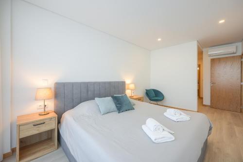 阿威罗Alameda 74 Luxury Apartment by Home Sweet Home Aveiro的一间卧室配有一张大床和两条毛巾