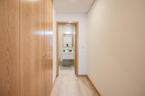 阿威罗Alameda 74 Luxury Apartment by Home Sweet Home Aveiro的浴室内带门和水槽的走廊