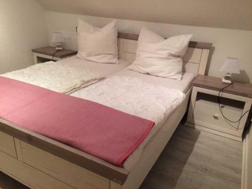 蒂门多弗施特兰德Ferienwohnung Möwennest的一张铺有白色床单和红色毯子的床